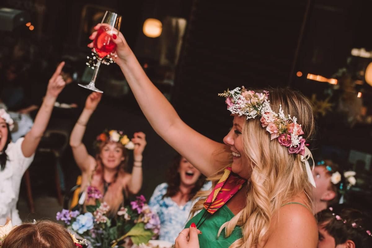 Raising a glass in a flower crown at a midsummer dinner