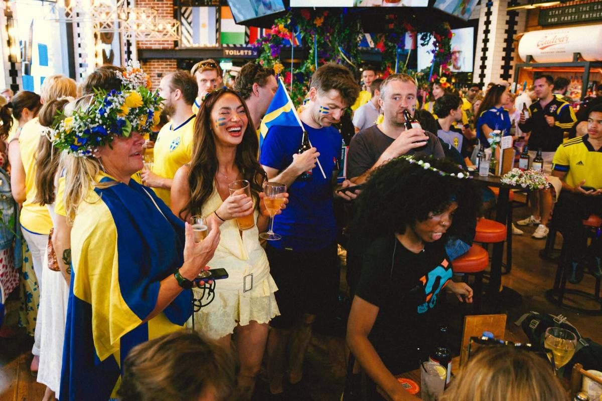 A packed Swedish midsummer celebration in London with flower crowns and blue-and-yellow colours